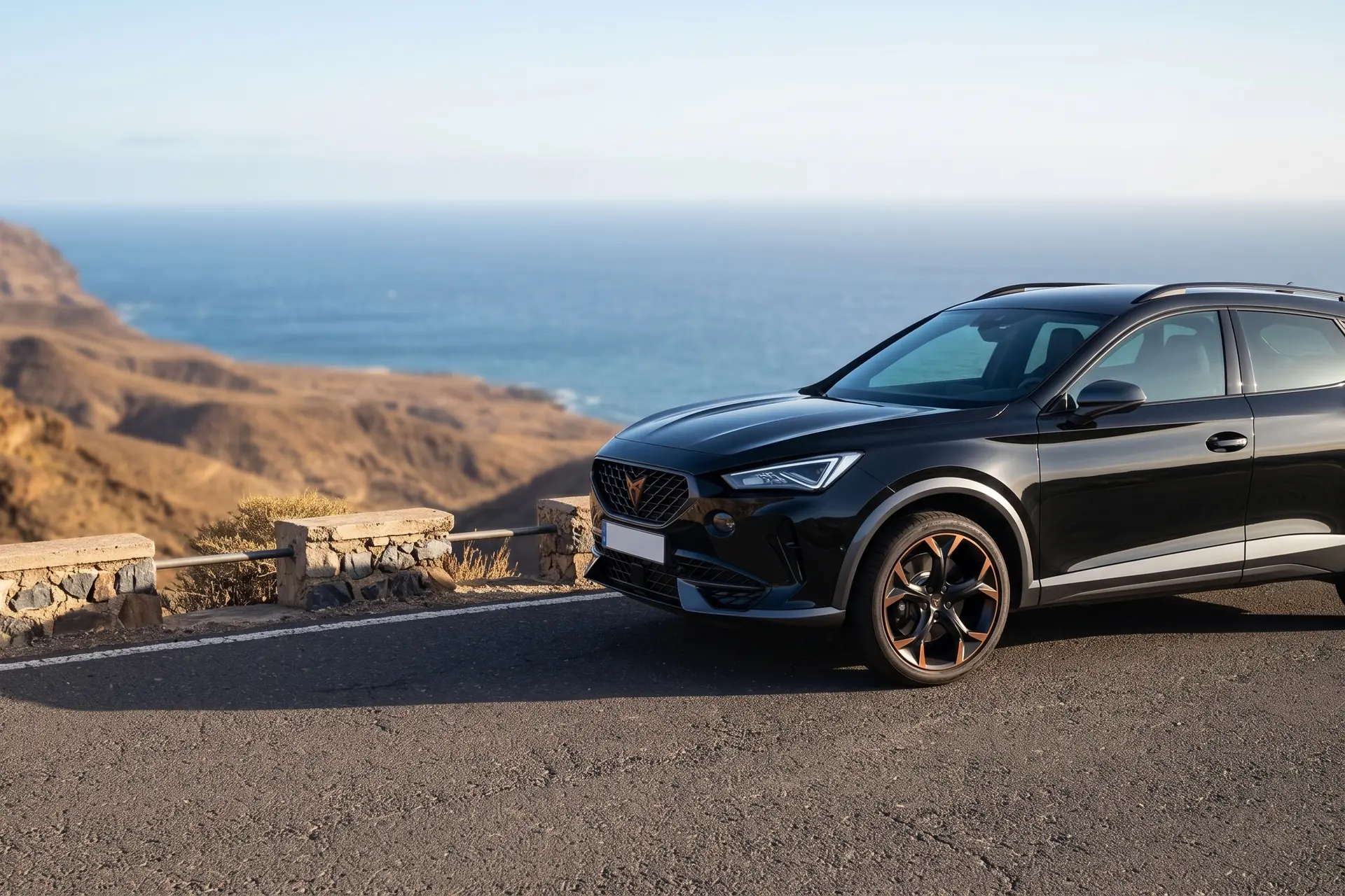 Un SUV negro aparcado en un mirador de una carretera de la costa de Gran Canaria, con el acantilado y el mar al fondo.